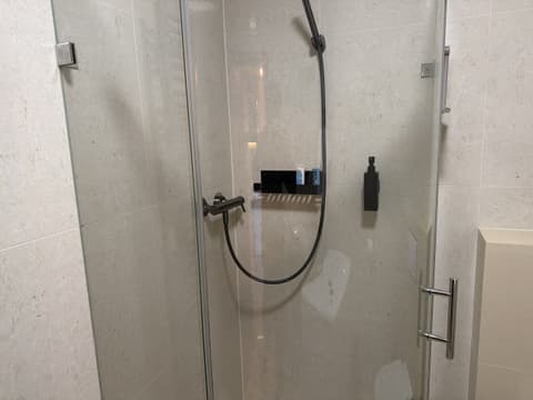 Shower with glass doors, stone-look tiles and black fittings