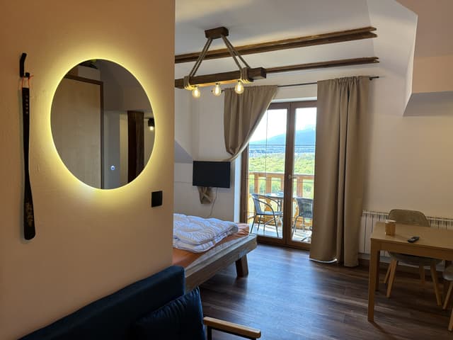 The studio with the double bed, beam lamp and balcony door open to the mountains