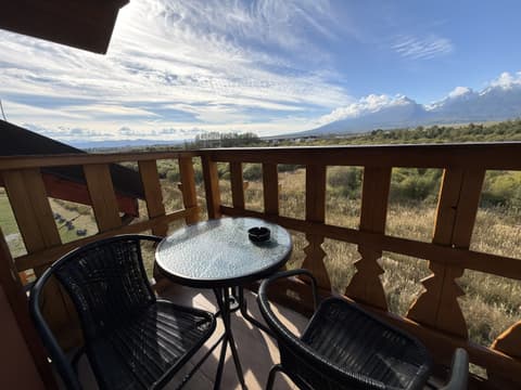 Balcony with a glass table and two chairs looking at the High Tatras